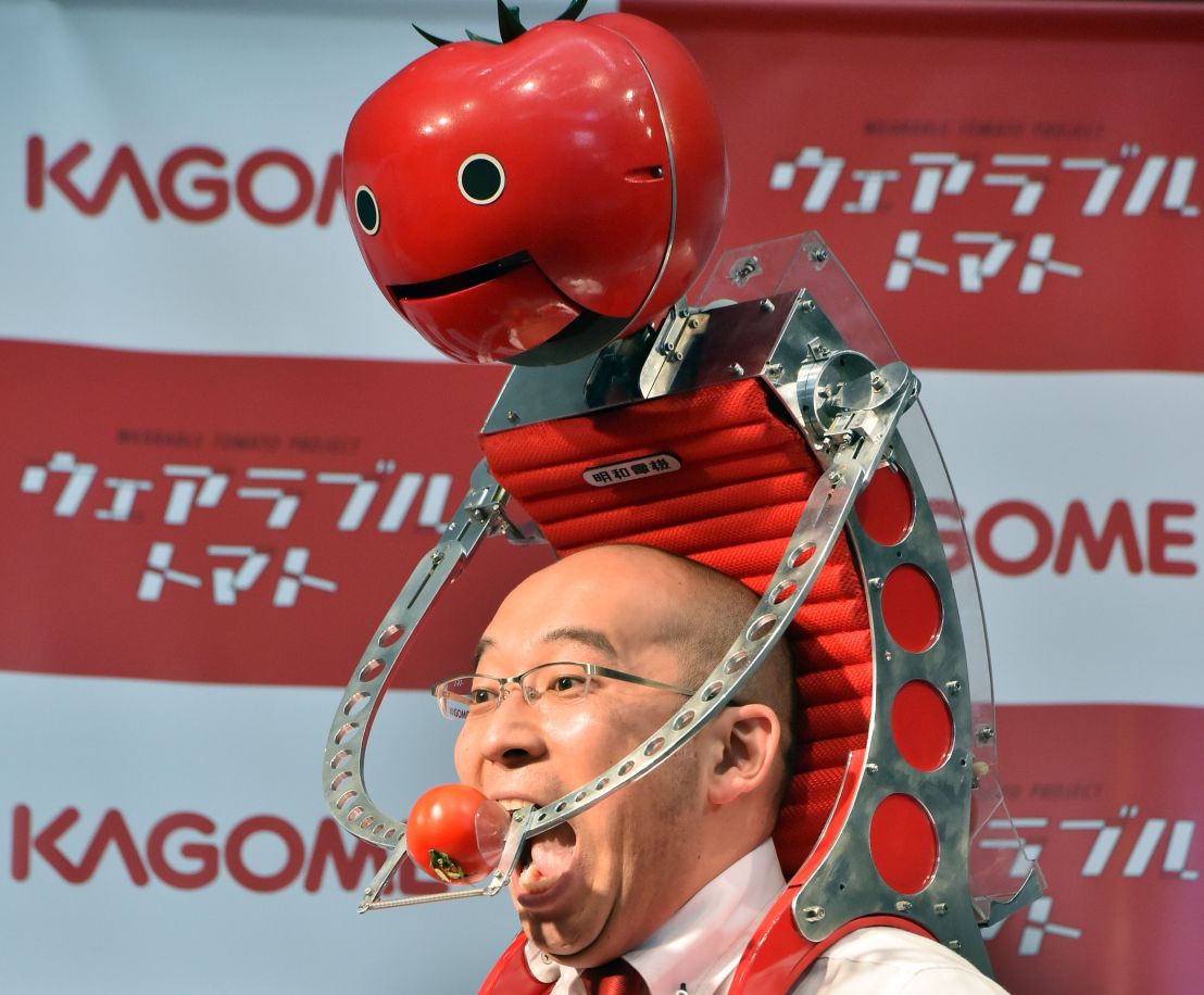 Japan's food company Kagome employee Shigenori Suzuki tries to eat a tomato which is provided from the newly developed tomato dispenser for marathon runner &quot;Tomachan&quot; during a demonstration ahead of this weekend's Tokyo marathon in Tokyo on February 19, 2015. The hands free tomato eating machine was developed by Japanese artist Nobumichi Tosa and Tosa also developed a compact one &quot;Mini-Tomachan&quot;.     AFP PHOTO / Yoshikazu TSUNO